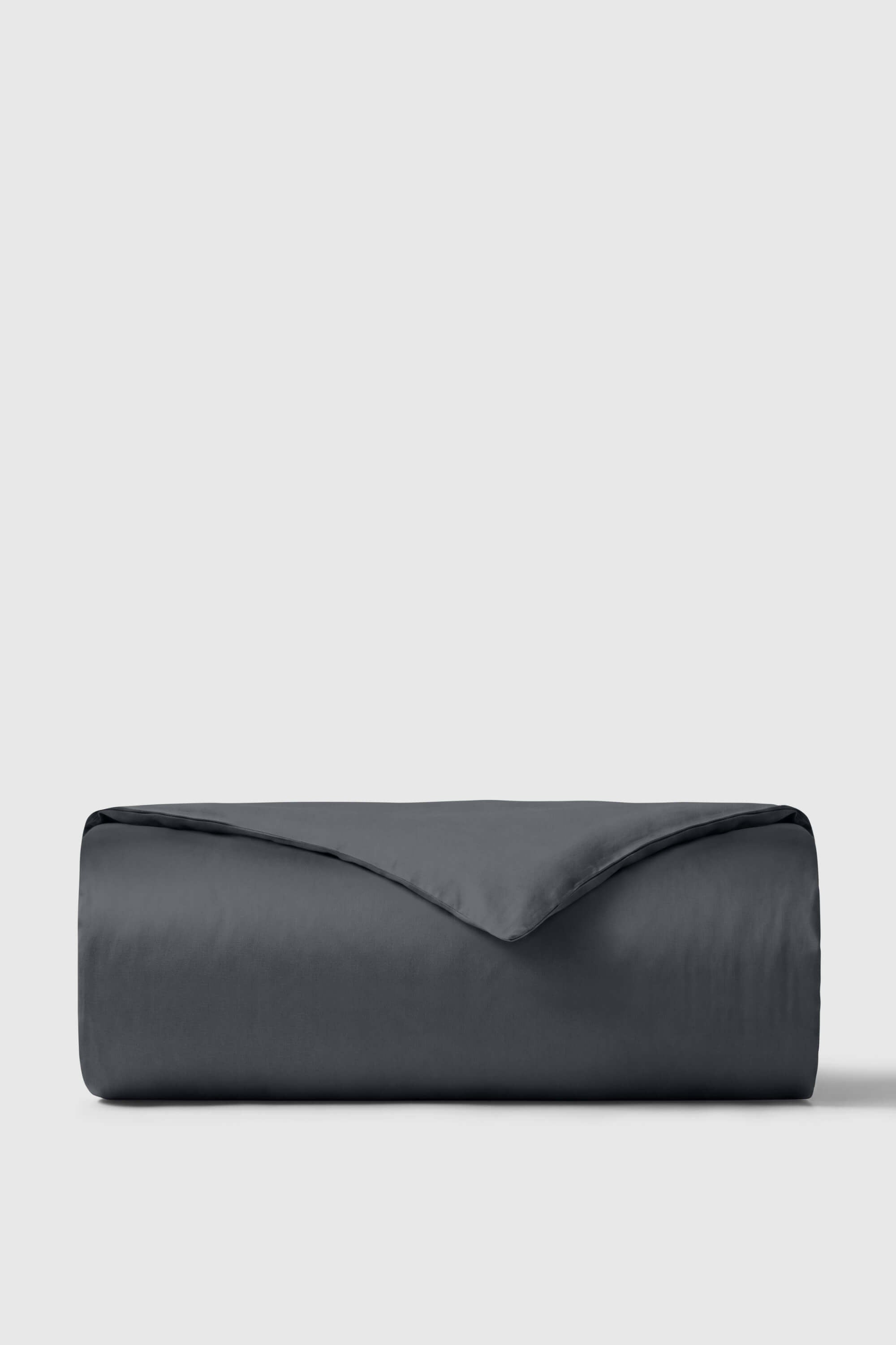 Dark gray sateen duvet cover neatly rolled against a neutral background perfect for stylish bedroom decor