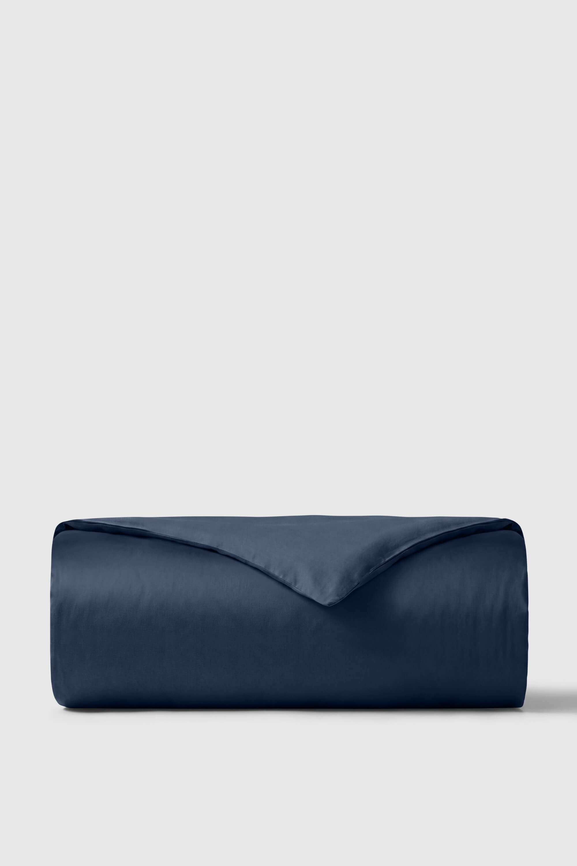 A navy blue sateen duvet cover rolled to show its smooth and luxurious satin texture