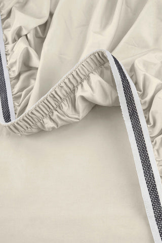 Beige elastic bedsheet with black and white striped trim from the sateen essentials bedding set