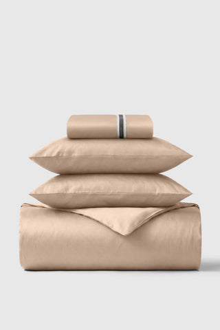 Beige satin sheet set with subtle striped accent band on pillowcase in the sateen essentials bedding set