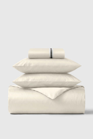 Cream-colored cotton sateen essentials bedding set with subtle black stripe detail on pillowcase for cozy sleep