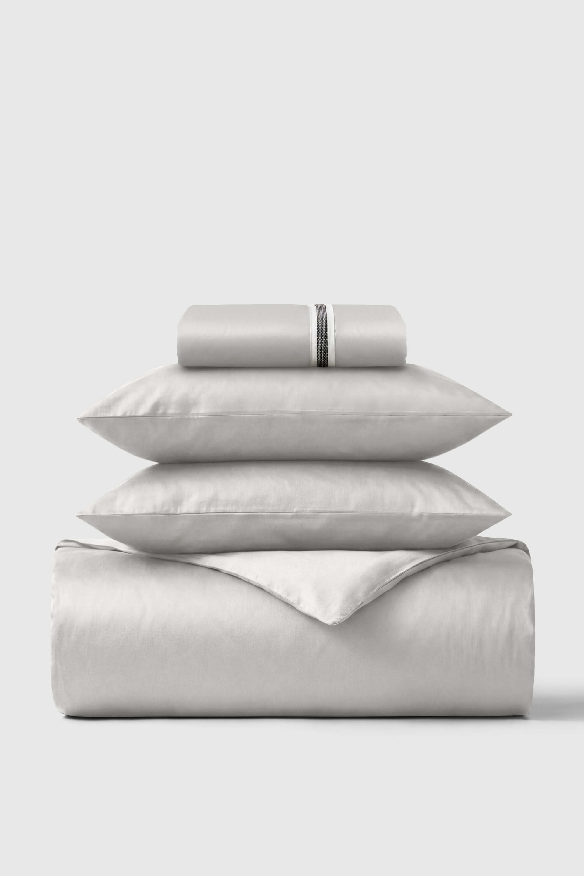 A sleek silver-gray satin essentials bedding set with subtle textured stripe detail on the pillowcase