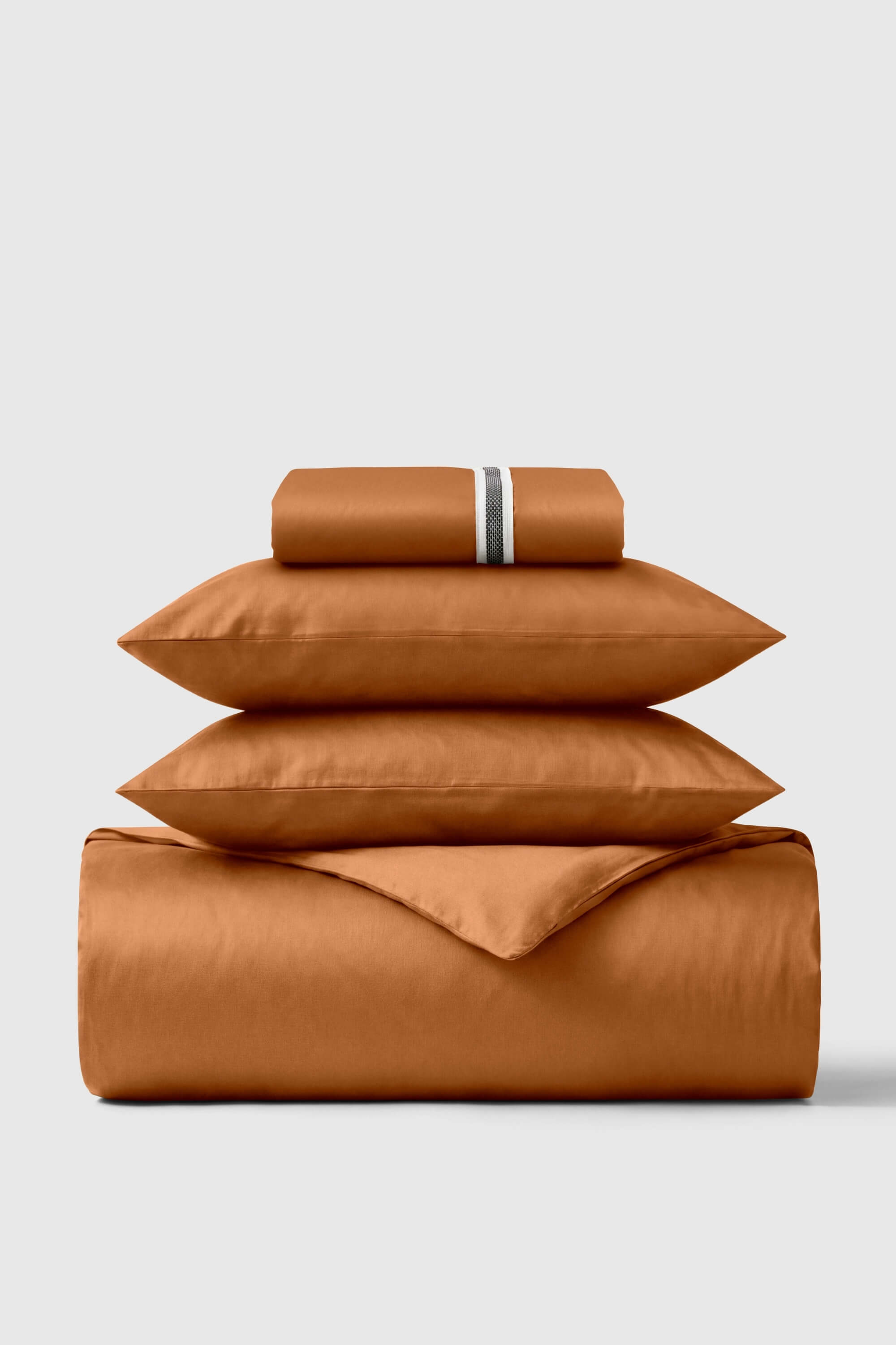 A luxurious rust-colored satin sheet set with sheen and silver stripe pillowcase in sateen essentials bedding