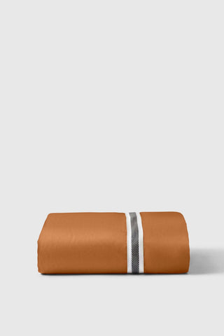 A neatly folded orange sateen fitted sheet with a central stripe featuring white and textured gray bands