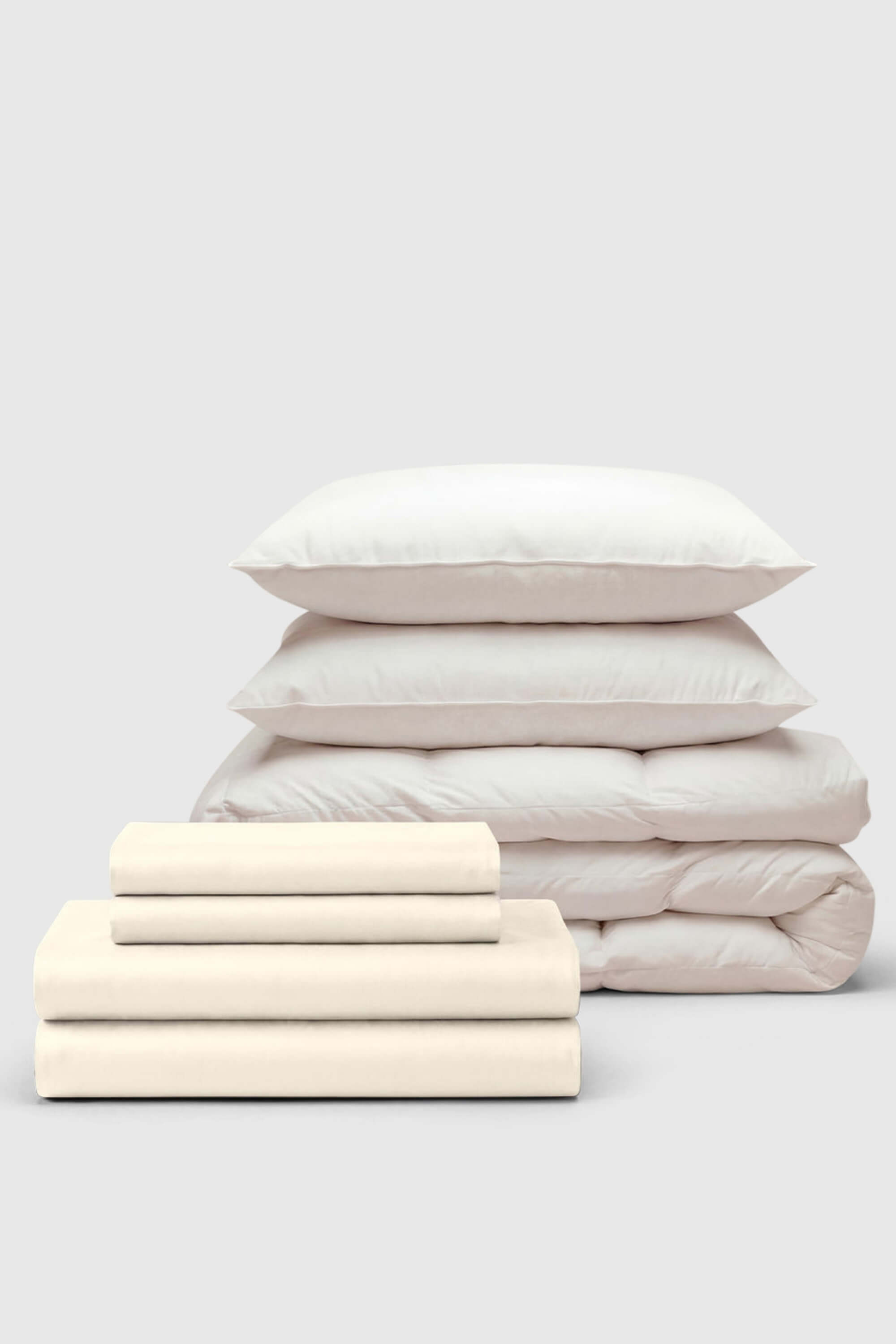 Cream-colored cotton sateen move-in bedding set with matching pillows and quilted duvet for cozy comfort