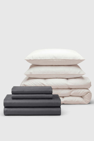 Neutral-toned sateen move-in bedding set with crisp white pillows and a dark gray duvet cover neatly folded