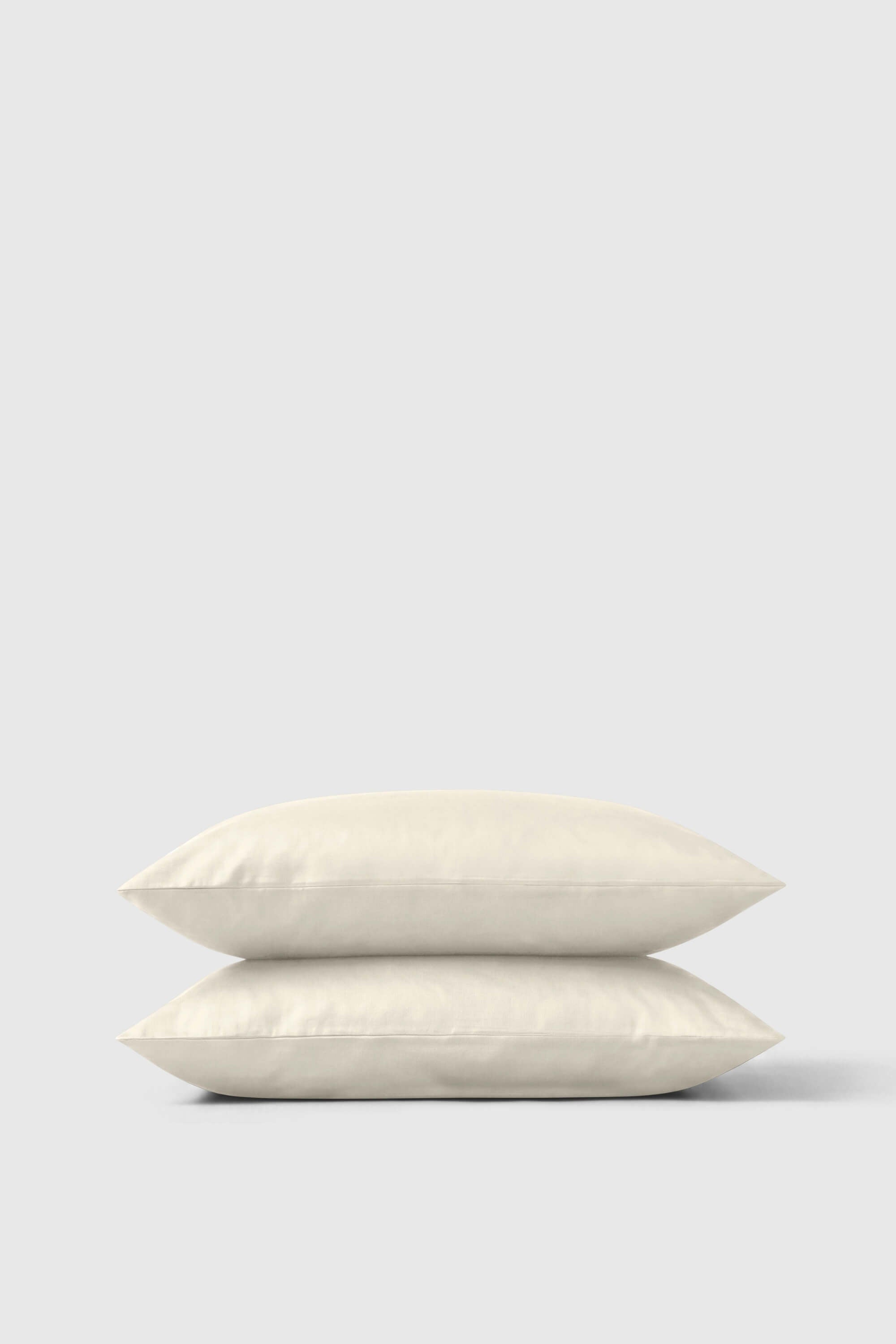 Cream-colored soft-textured sateen pillowcase pair neatly stacked perfect for a cozy bedding set