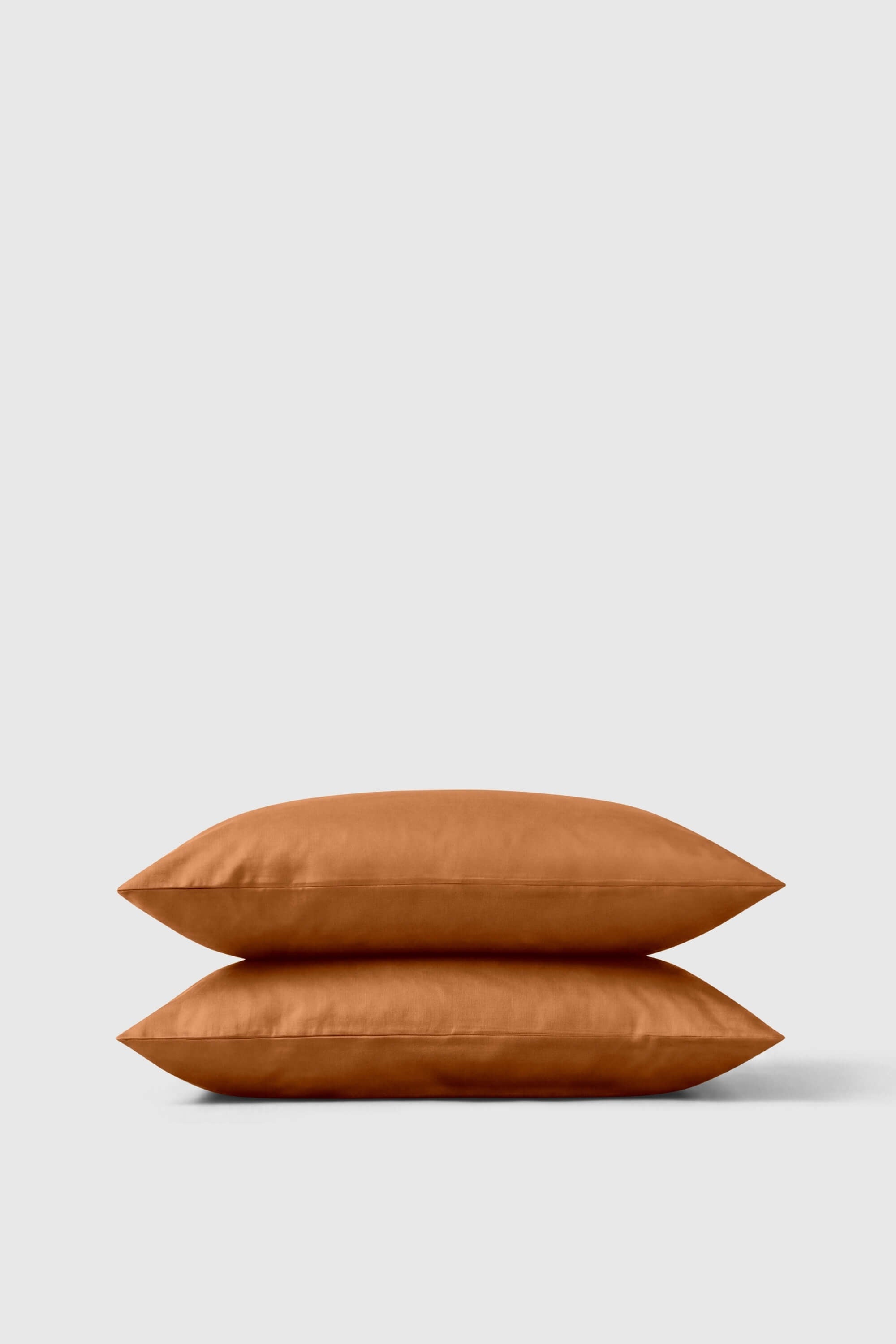 A rust-colored satin finish sateen pillowcase pair stacked neatly for a soft and stylish bedroom look