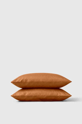 A rust-colored satin finish sateen pillowcase pair stacked neatly for a soft and stylish bedroom look