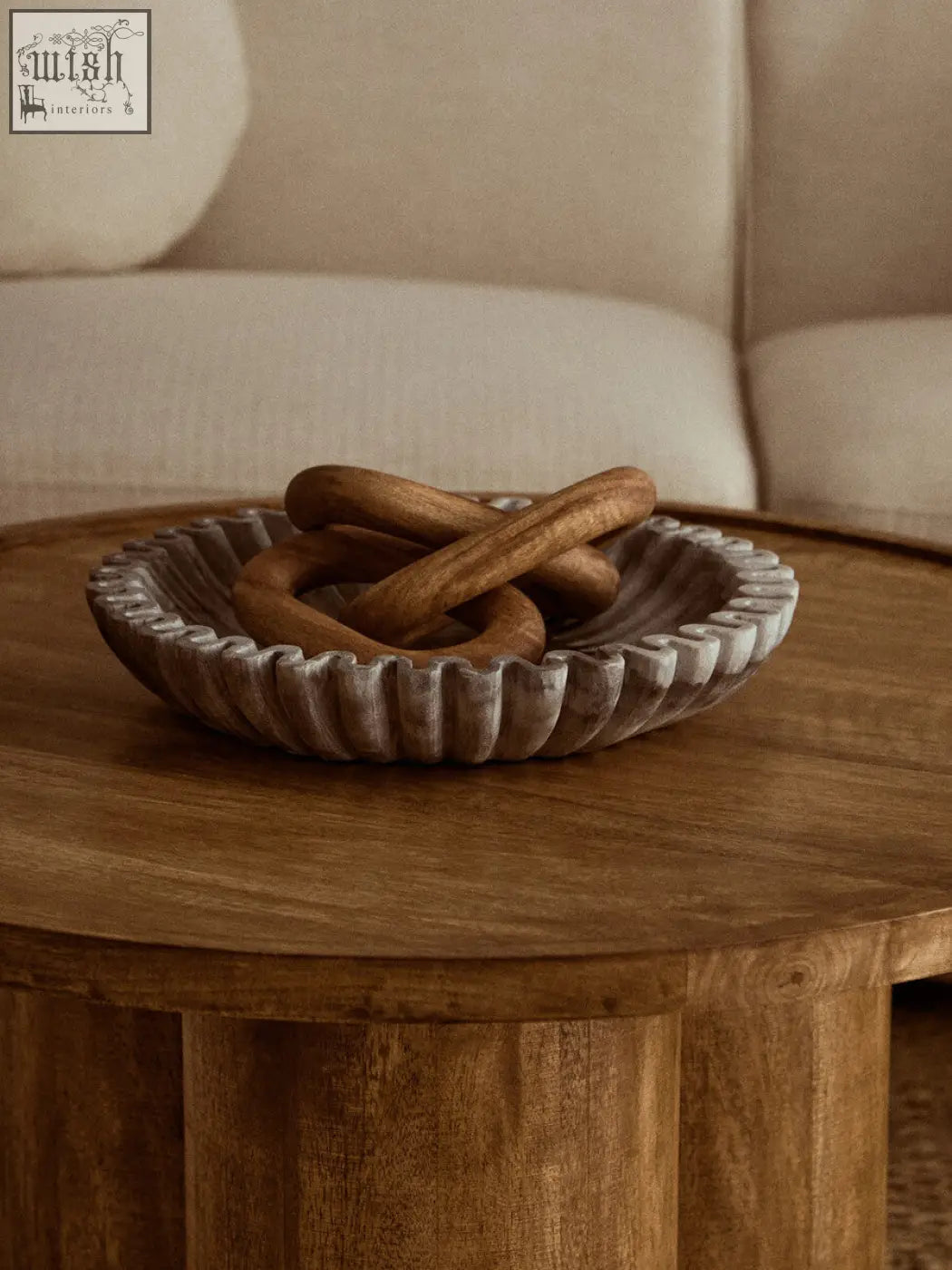 A rustic grey fluted marble bowl holding wooden rings perfect for compact surfaces and stylish storage