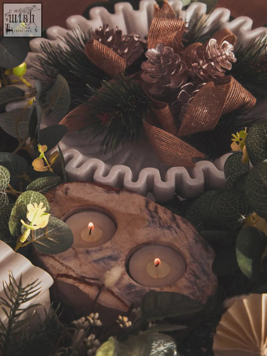 A rustic wooden candle holder with two lit tealight candles beside a savio large white marble bowl