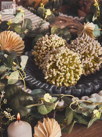 Two heart-shaped dried flower arrangements in a dark bowl beside a white marble savio rectangular box with grey veining