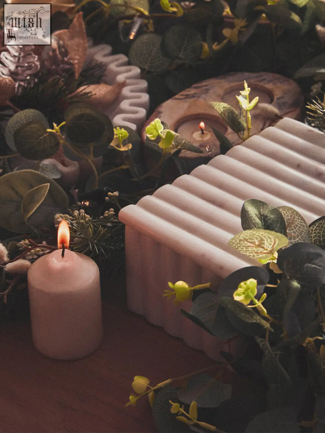 A pink ribbed soap bar with a smooth matte finish resting in a white marble box with grey veining and greenery