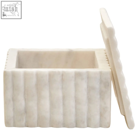A cream-colored fluted marble box with vertical ribbed texture and matching scalloped lid for stylish storage