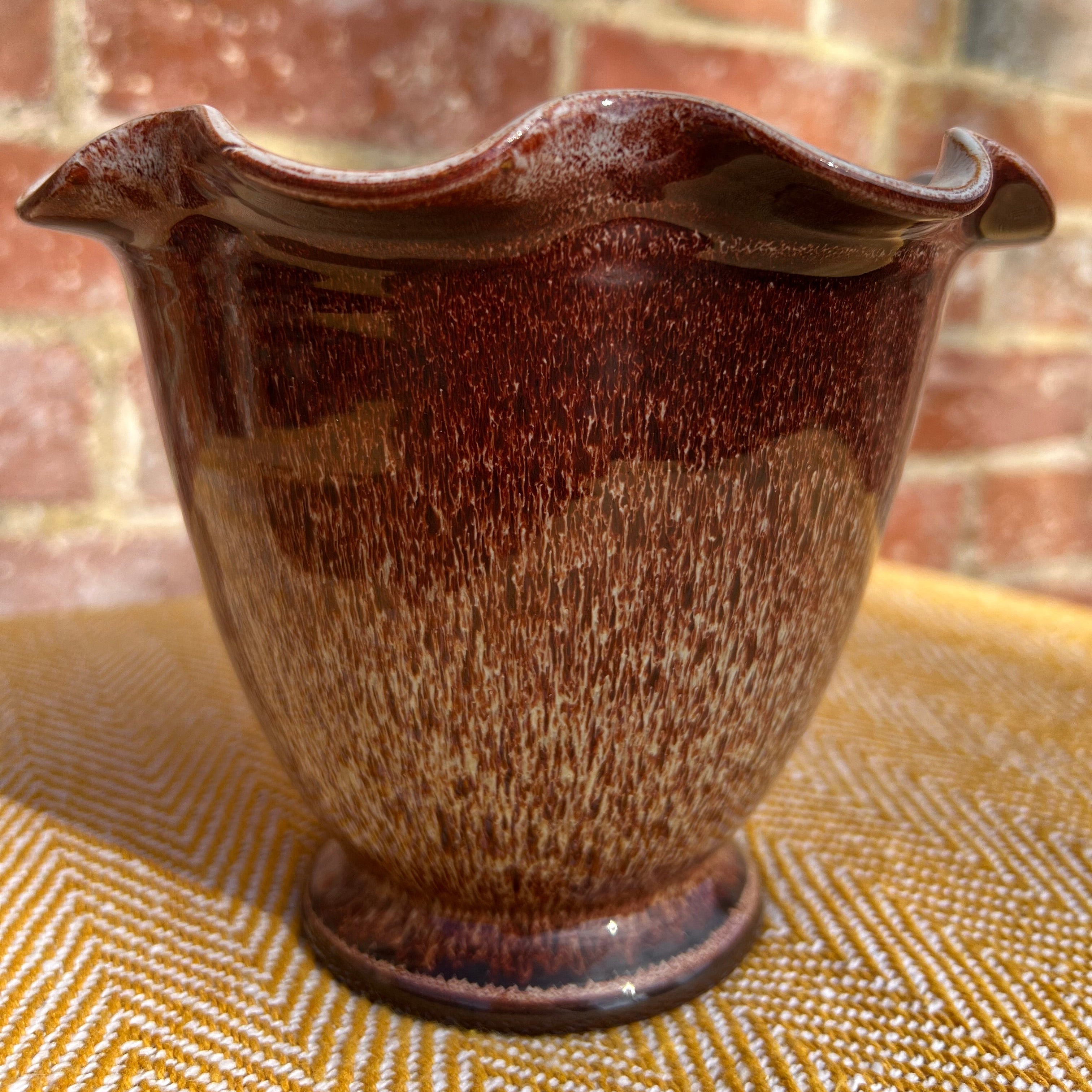 A glossy brown ceramic scalloped vase with a wavy fluted rim and speckled glaze perfect for decor
