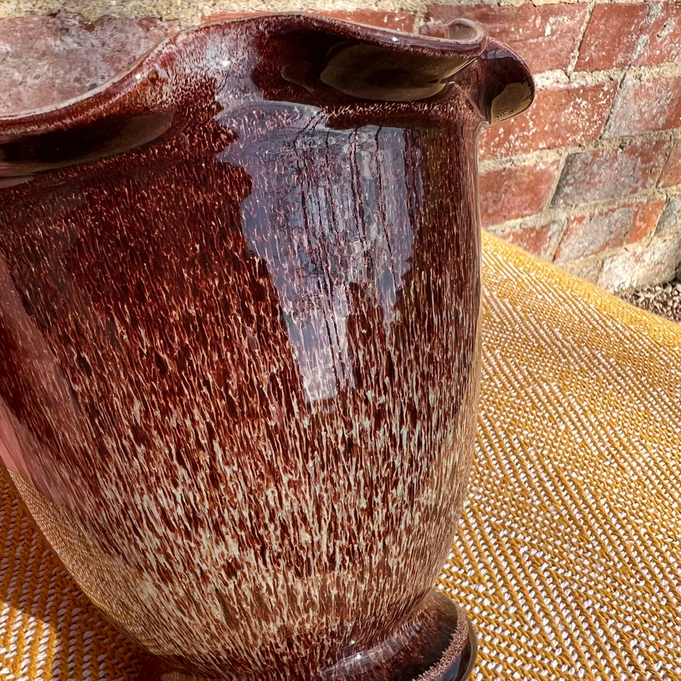 A scalloped brown ceramic vase with a glossy deep reddish-brown speckled glaze and a flared rim pitcher shape