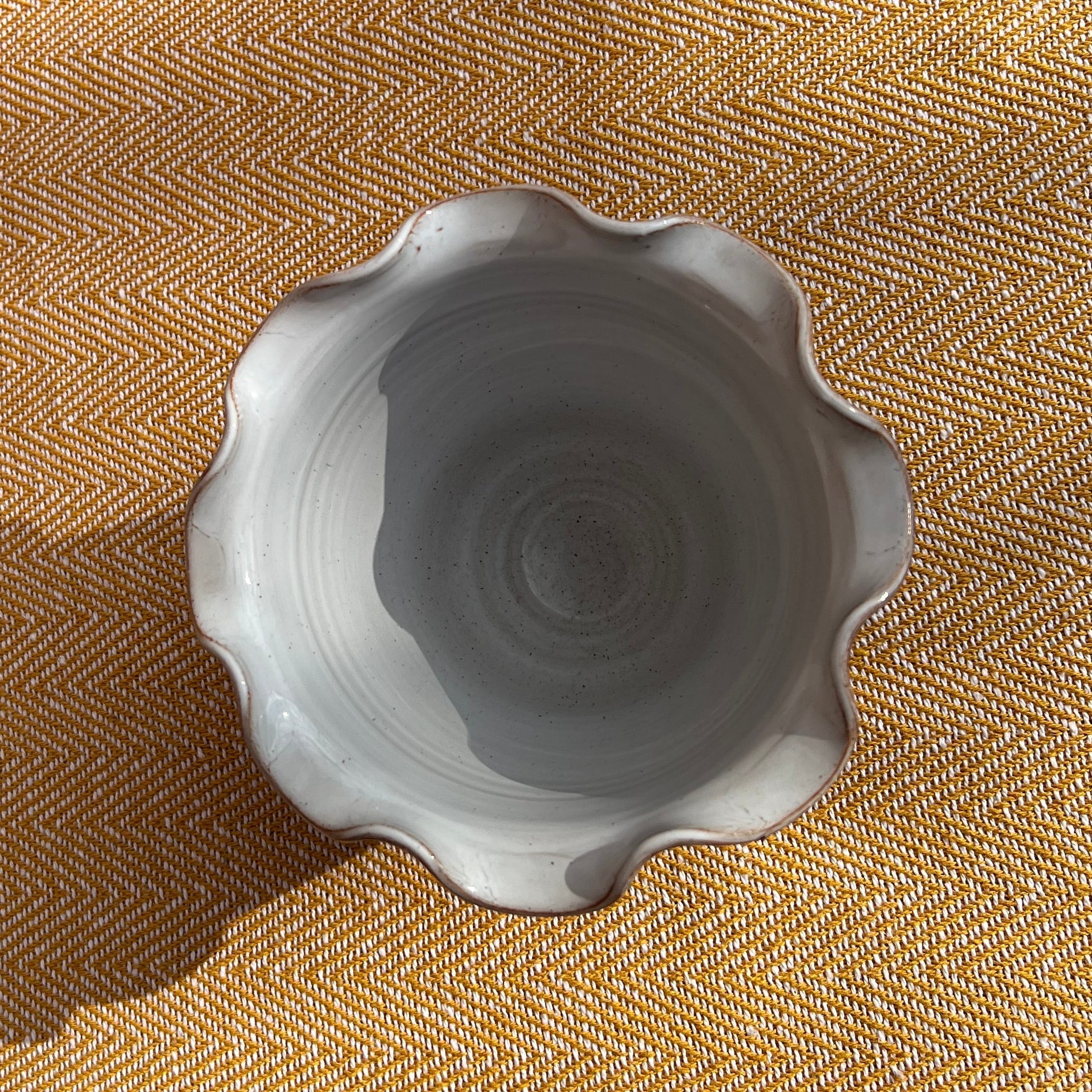 A light gray ceramic scalloped bowl with subtle speckles shown as a scalloped brown vase pot alternative