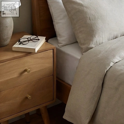 Beige linen duvet cover with soft textured weave and natural folds next to scandinavian light walnut logan narrow bedside table