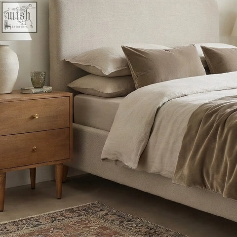 Beige upholstered bed with matching pillows and velvet throw next to a scandinavian light walnut oslo bedside table