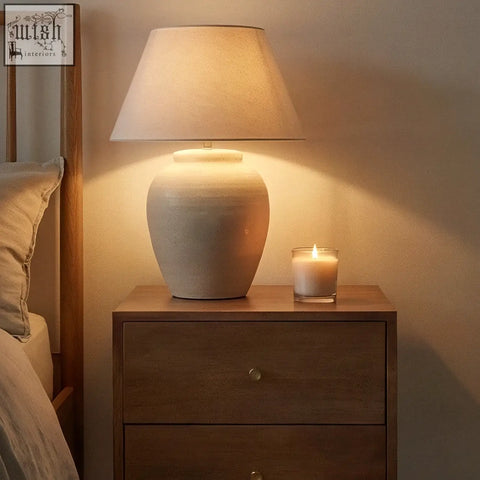 Cream-colored ceramic table lamp with textured tapered shade on scandinavian light walnut oslo bedside table