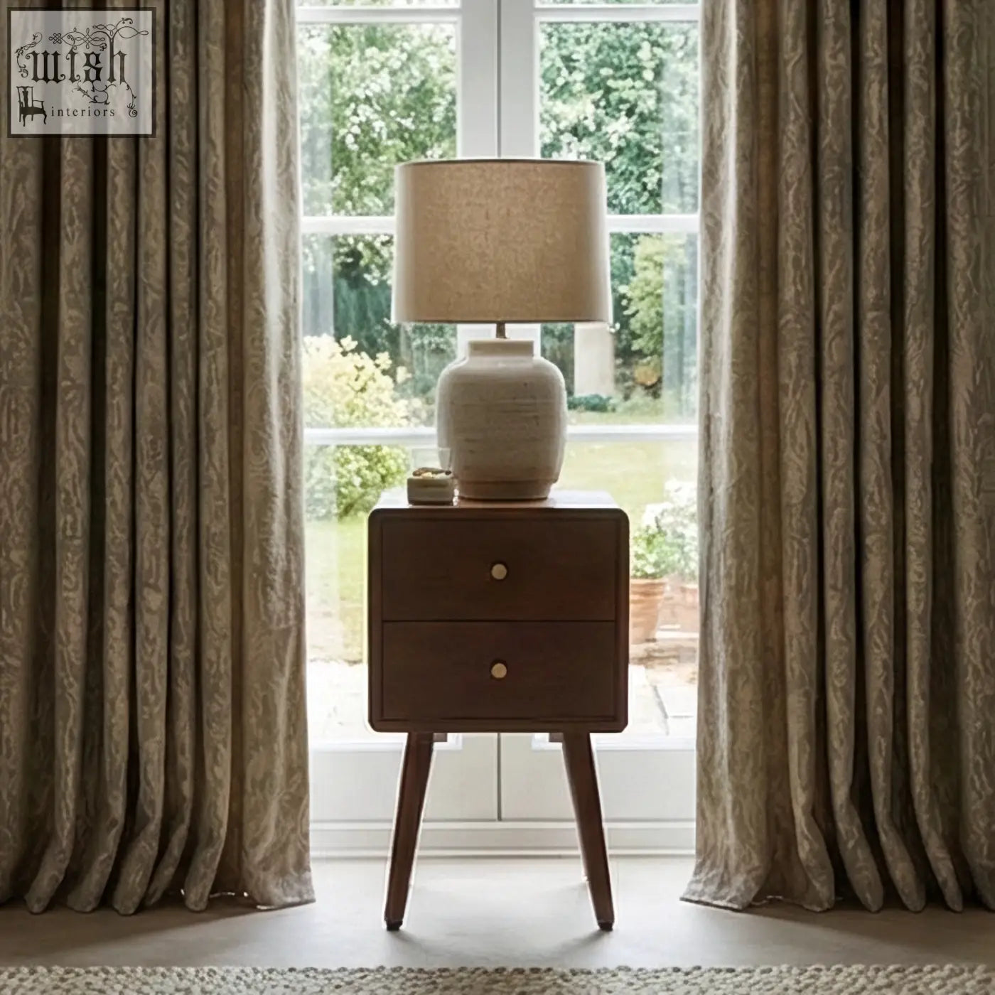 A beige ceramic table lamp with a textured shade sits on a scandinavian walnut logan narrow bedside table measuring 30cm wide
