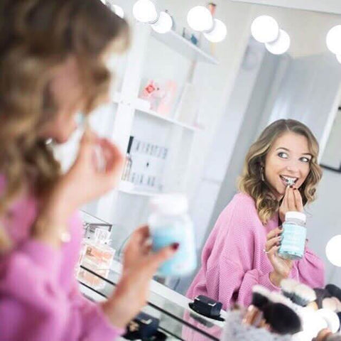 A woman in a pink sweater holding a light blue jar in front of a scarlett large hollywood mirror 100x70cm