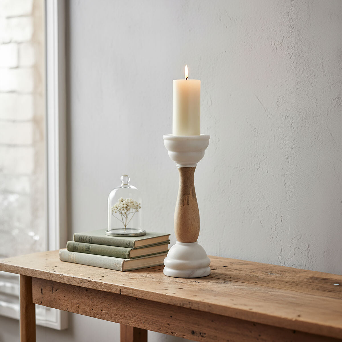 Sena candle holder with a white marble base and mango wood column holding an ivory pillar candle