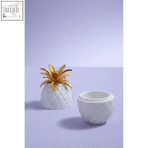 White ceramic sena pineapple jar with gold leaf crown resembling a white marble pineapple jar container