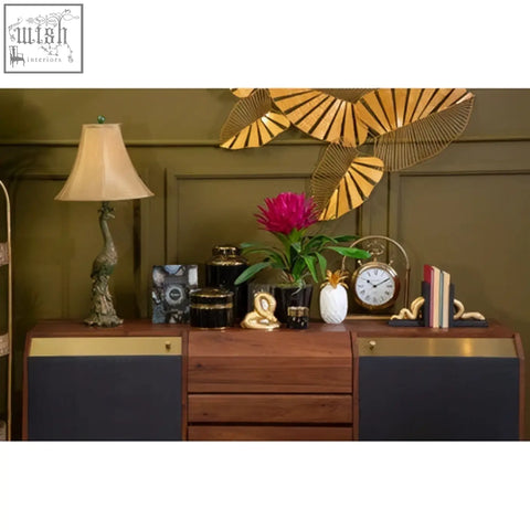 Wooden sideboard with dark blue panels and brass accents next to a white marble sena pineapple jar