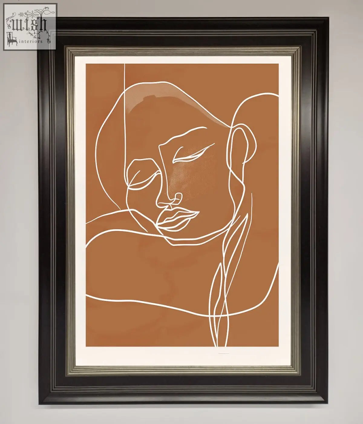 A minimalist sepia lines framed wall art with a white line drawing of a face on an earthy brown background
