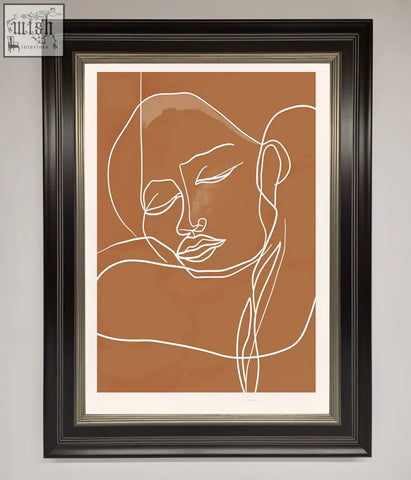 A minimalist sepia lines framed wall art with a white line drawing of a face on an earthy brown background