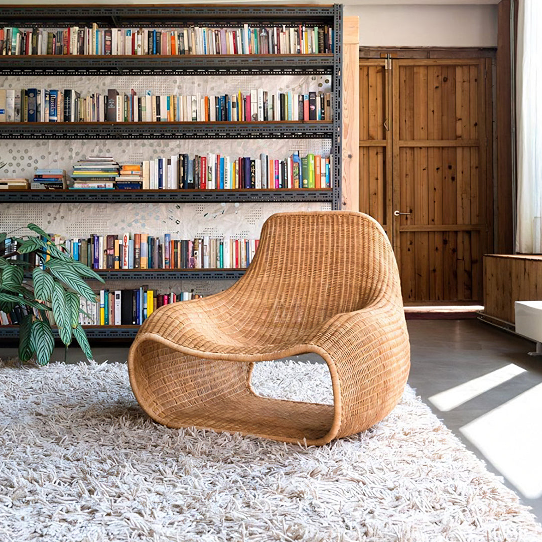 A sleek light brown rattan serrano outdoor lounge chair with footstool and modern sculpted design on white rug