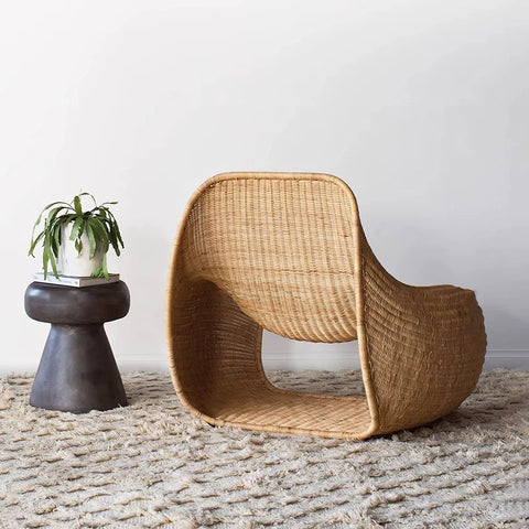 A sleek light brown woven rattan lounge chair with modern curved design for outdoor use with footstool