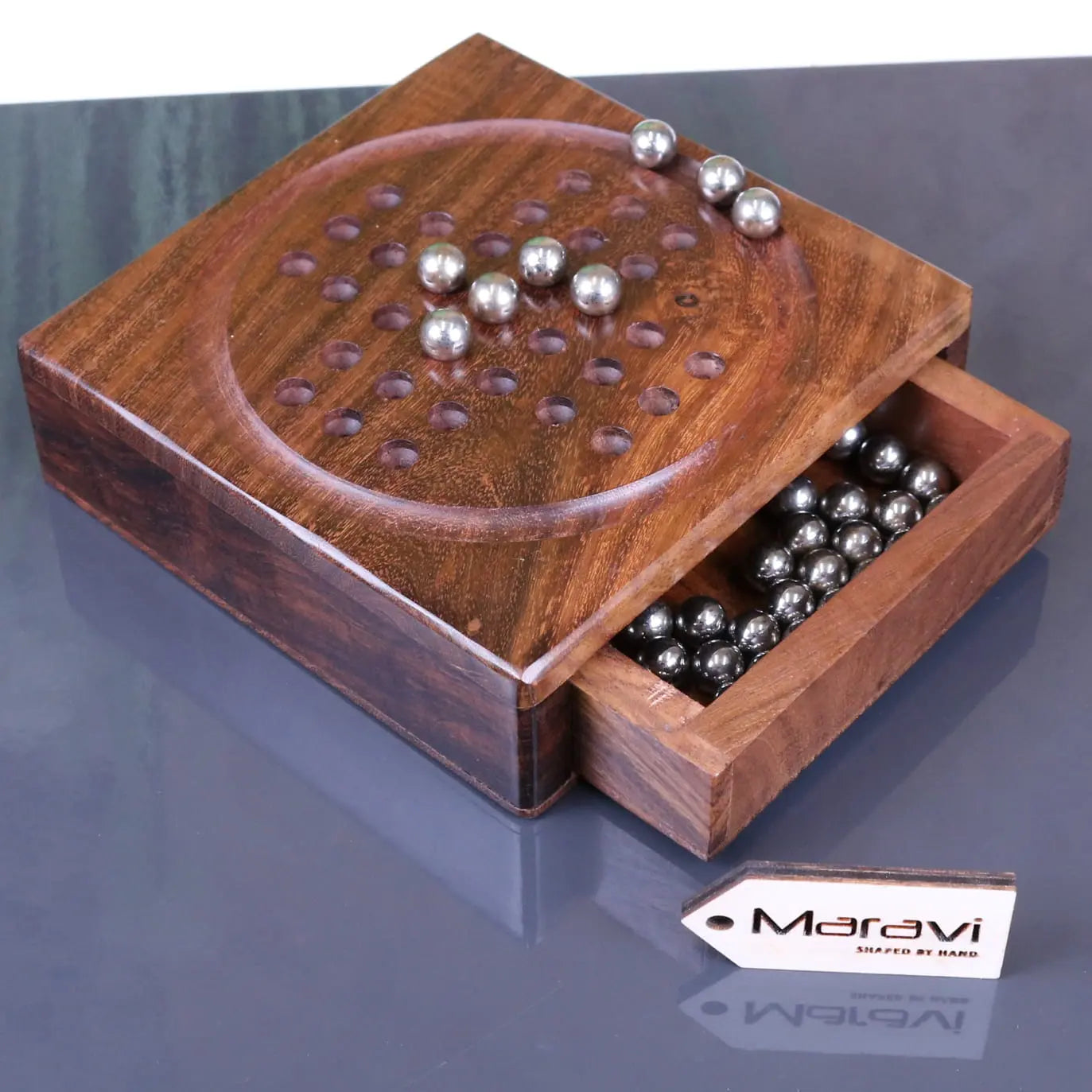 Handcrafted wooden sesih pocket solitaire game with circular playing surface metal balls and drawer with extra spheres