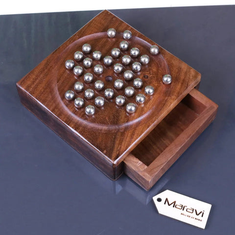 A polished dark wood pocket solitaire game with a circular othello board and shiny silver steel marble discs