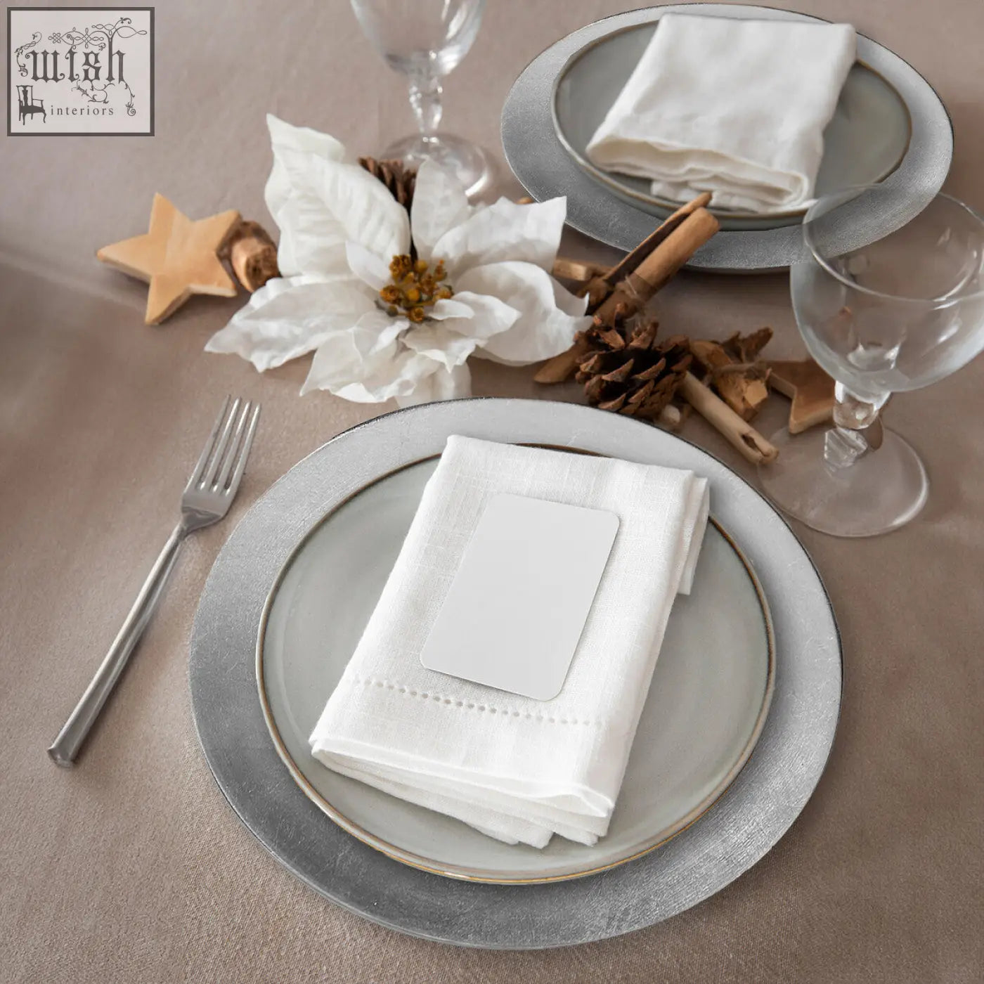 White linen napkin with subtle embroidered edge on silver charger plates with distressed finish to protect table surfaces