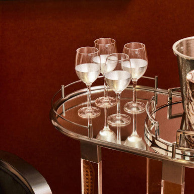 Six clear apollo large wine glasses filled with white wine on a mirrored serving cart for elegant serving