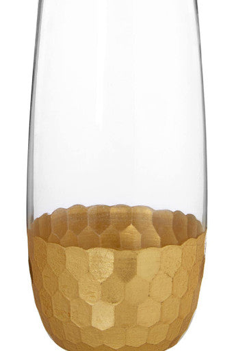 A clear glass champagne flute with a gold hexagonal base from the set of four astrid highball glasses