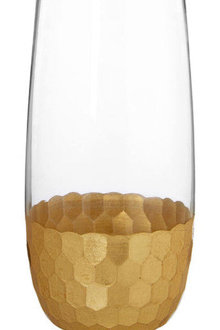 A clear glass champagne flute with a gold hexagonal base from the set of four astrid highball glasses