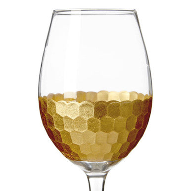 A clear astrid large wine glass with a gold hexagonal patterned band around the lower half from a set of four large wine glasses