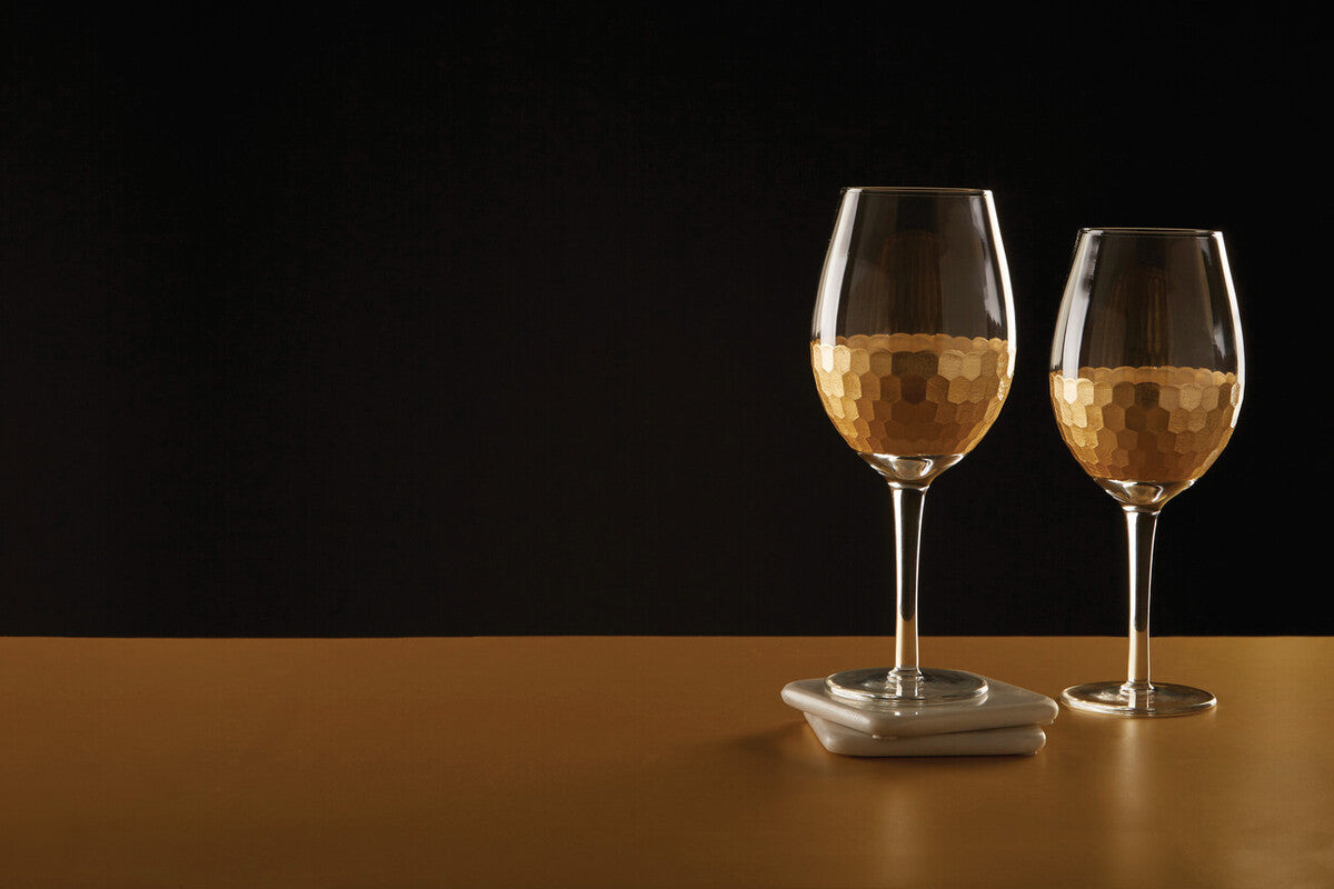 Two elegant astrid large wine glasses with hammered gold finish and golden liquid filled for stylish wine sipping