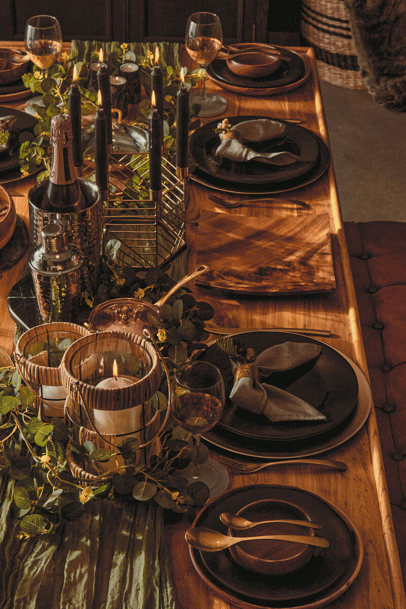 Dark matte black ceramic plates with gold rim edges on a rustic table paired with astrid small wine glasses set of four