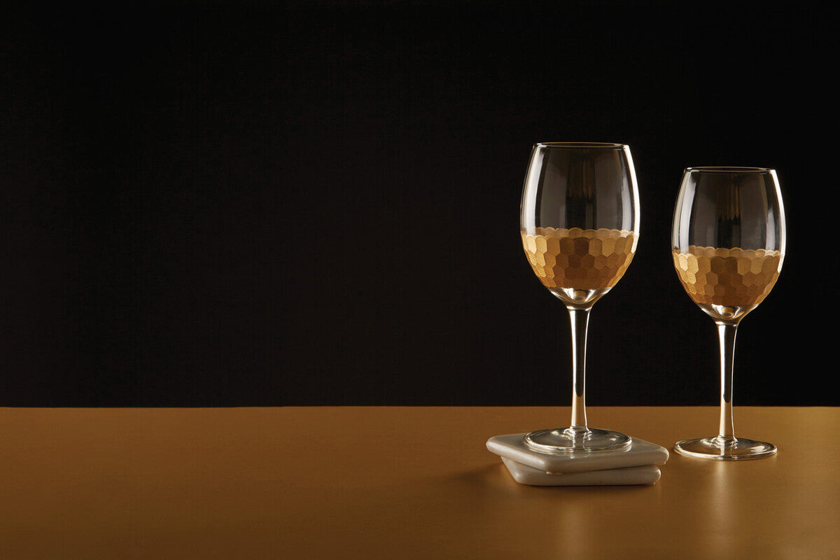 Two astrid small wine glasses with hammered gold finish on lower half filled with pale golden liquid