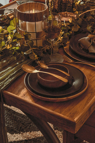 Warm-toned ceramic bowl with matte finish resting on stacked plates near a set of four astrid small wine glasses