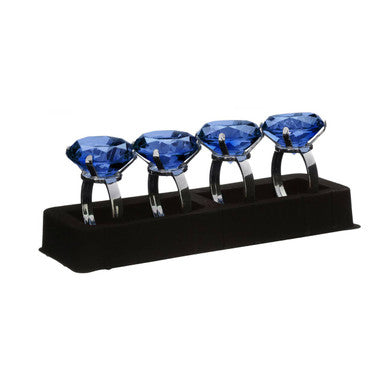 Set of four sapphire diamante napkin rings with blue gemstone and silver-toned bands on a black base