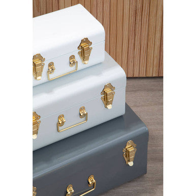 Set of three assorted grey storage trunks in white light blue and dark gray with gold-tone hardware for stylish storage