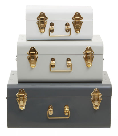 Stacked set of three assorted grey storage trunks in vintage metal with gold-tone hardware for stylish storage