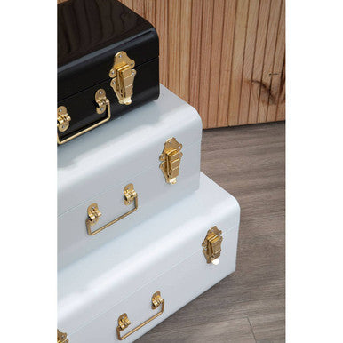 Stacked vintage style storage trunks in glossy black and matte white with ornate gold hardware in three monochrome storage trunks set
