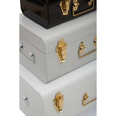 Stacked three monochrome storage trunks in glossy white black and grey with gold-toned hardware for stylish storage