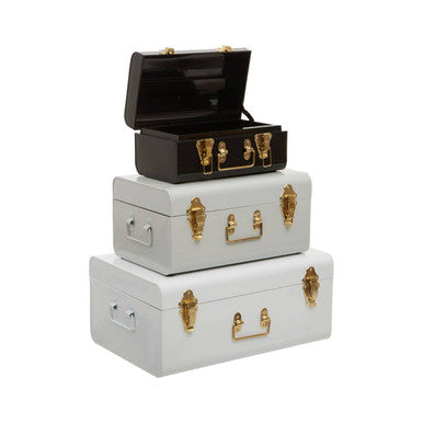 Stacked white and black metal storage trunks with gold hardware forming a set of three monochrome storage trunks